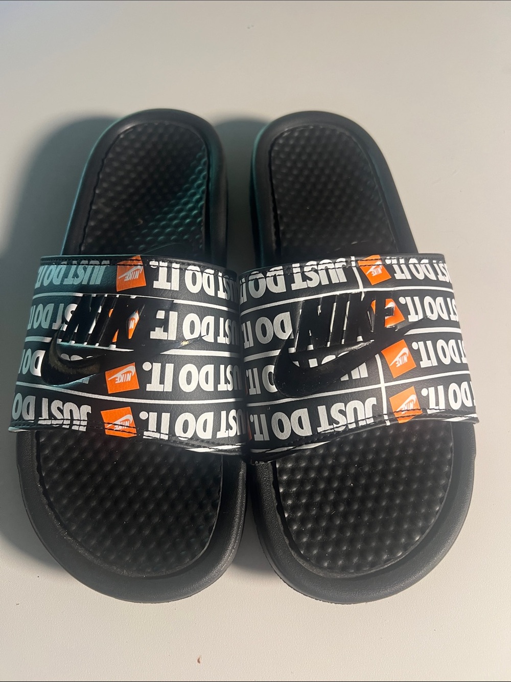 Nike Kids Black Slides with White 'Just Do It' Print and Orange Accents